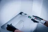 A person wearing black gloves is using a digital angle finder with a spirit level to measure an internal corner of a white structure. Anteprima dell’immagine prodotto