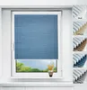 A blue pleated blind is shown on a window, with a small vase of flowers on the windowsill below. To the right, there are swatches of different colored blinds. Produktbild-Vorschau