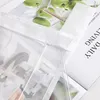 A close-up view of a transparent bag containing a magazine, with a close-up of green apples visible through the bag. Text from the magazine is also visible. Produktbild-Vorschau