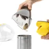 A hand is emptying dust from a handheld vacuum cleaner's dustbin into a metal container. Anteprima dell’immagine prodotto