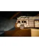 A wooden model fire truck is placed on a wooden surface with a dark, blurred background. Produktbild-Vorschau