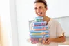 A woman is holding a stack of food storage containers filled with colorful food items. Náhľad obrázku produktu