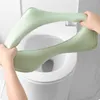 Hands holding a green toilet seat cushion over a white toilet. Podgląd zdjęcia produktu