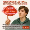 A young person is looking at a flying LED ball. Produktbild-Vorschau