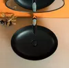 A black ceramic sink with a modern faucet, set against an orange tiled wall and a wooden countertop. Náhľad obrázku produktu