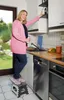 A woman is using a step stool in a kitchen to reach into a cabinet. Podgląd zdjęcia produktu