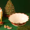 A Christmas-themed table setting with a decorative ceramic Christmas tree, a candle, a serving bowl, and small angel figurines. Náhľad obrázku produktu