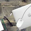 A white computer mouse and a white USB-C cable are connected to a silver laptop on a wooden desk. A pair of black-rimmed glasses and a green pencil are also on the desk. Produktbild-Vorschau