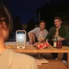 People enjoying a movie night outdoors with a projector, snacks, and drinks. Produktbild-Vorschau
