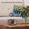 A retro radio sits on a wooden table in front of a couch with a decorative pillow and flowers. Produktbild-Vorschau