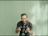 A man is holding a plumbing component in front of a light green wall. Podgląd zdjęcia produktu
