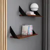 Two modern shelves mounted on a gray wall, displaying books and a lamp. Náhled obrázku produktu