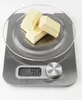 Three pieces of white chocolate on a digital kitchen scale. Anteprima dell’immagine prodotto