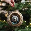A hand holding a Christmas ornament shaped like a hollowed-out log with a bear inside, hanging on a Christmas tree. Produktbild-Vorschau