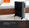 An oil-filled radiator is placed on a fluffy white rug next to a bed. The image has a dark gray overlay at the bottom with text and a graphic. Náhled obrázku produktu
