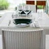 A table setting with plates, glasses, and cutlery on a patio or outdoor dining area. Produktbild-Vorschau