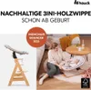 A woman is interacting with a baby in a bouncer next to a high chair, in a living room setting. Produktbild-Vorschau