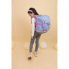 A young girl wearing a backpack walks away from the camera against a plain yellow background with balloons. Produktbild-Vorschau