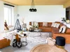 A living room scene with a large sectional sofa, coffee table, ottoman, and decorative items. Náhled obrázku produktu