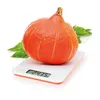 A pumpkin is being weighed on a digital kitchen scale, with green leaves in the background. Produktbild-Vorschau