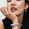 A close-up shot of a woman wearing Pandora jewelry, including rings, a bracelet, and an earring, with a focus on the colorful beads of the bracelet and earring. Anteprima dell’immagine prodotto