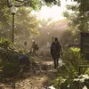 Two people walking on a muddy path in a park with lush greenery and sunlight filtering through the trees. Produktbild-Vorschau