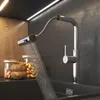 A modern kitchen sink with a pull-out faucet spraying water, next to jars of nuts and wooden bowls. Produktbild-Vorschau