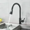 A black kitchen faucet with a pull-down sprayer is shown in use, with water flowing into a stainless steel sink. Produktbild-Vorschau