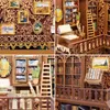A collage of four images showing different parts of a miniature DIY book nook kit, including furniture, books, and decorative elements. Voir les images du produit