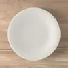 A white plate is centered on a wooden surface. Náhľad obrázku produktu