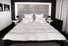 A neatly made bed with a white duvet and pillows in a modern bedroom setting. Produktbild-Vorschau