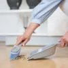 A person is sweeping debris from a wooden floor with a hand brush and dustpan. Náhled obrázku produktu