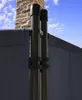 A close-up view of a gray fabric privacy screen supported by dark poles, with a brick chimney and blue sky in the background. Produktbild-Vorschau