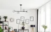 A modern living room with a black chandelier, shelves with plants and decor, and a floor lamp. Produktbild-Vorschau