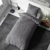 A neatly made bed with gray bedding in a room with a floor lamp and a rug. Produktbild-Vorschau