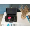 A vintage-style record player is set up on a white table, with a vase of dried flowers and books nearby. Voir les images du produit