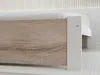 A close-up view of the corner of a bed frame, showing the wood grain texture and a white side panel. Náhled obrázku produktu