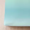 A close-up view of a seersucker bed linen with a gradient color effect, laid on a wooden surface. Produktbild-Vorschau