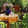 A table with a vase of flowers and a small plant on a balcony. Produktbild-Vorschau