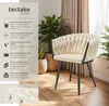 A cream-colored velvet armchair with a braided design is shown in a room setting with plants and curtains. Náhled obrázku produktu