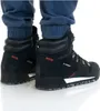A close-up view of a person wearing black Adidas Terrex hiking boots. Voir les images du produit