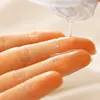 A close-up shot of a clear liquid being dispensed from a bottle onto a person's fingers. Podgląd zdjęcia produktu