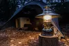 A camping scene at dusk with a lantern lit in the foreground and a tent in the background. Náhľad obrázku produktu