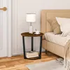 A round side table with a lamp and a cup of coffee next to a bed. Produktbild-Vorschau