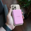 A hand holding a smartphone with a pink power bank attached to the back. Náhled obrázku produktu