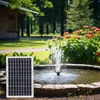 A solar panel is placed next to a garden fountain in a lush green garden setting. Náhled obrázku produktu