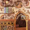 A close-up view of a miniature book nook kit, featuring decorative books on a shelf and an ornate archway. Voir les images du produit