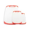 A set of three white cutting boards with orange trim and handles, arranged in a staggered formation against a white background. Anteprima dell’immagine prodotto