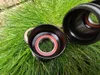 Two black bicycle bottom bracket cups with bearings are placed on green grass. Voir les images du produit