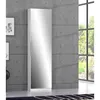 A tall, narrow white cabinet with a mirrored door stands against a concrete wall. A window with greenery is visible to the right. Anteprima dell’immagine prodotto